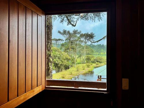 a window in a room with a view of a river at Vila Vert - Rancho Queimado - SC in Rancho Queimado