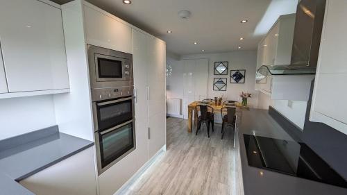 a kitchen with white cabinets and a table with chairs at Lane End Cottage Holmfirth - Panoramic Views, Modernised with offroad parking in Holmfirth