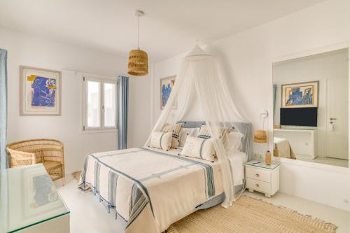 a white bedroom with a bed with a canopy at Villa Bellonia in Naousa