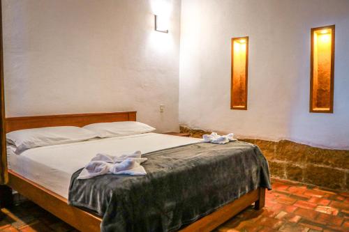 a bedroom with a bed with two towels on it at Hotel Tierra Roja By MH in Barichara