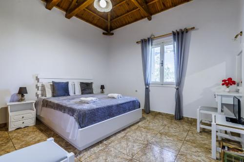 a white bedroom with a bed and a window at Anesis Apartment 1 in Panormos Skopelos