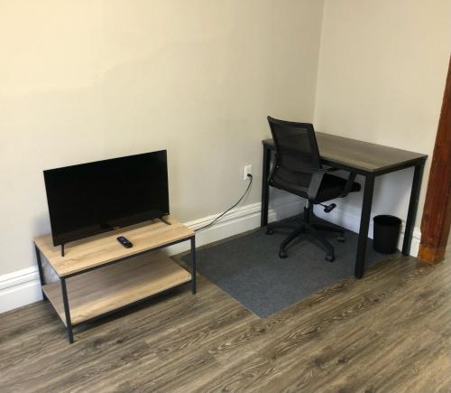 a desk with a television and a chair in a room at Private 2-bedroom apartment and New York City Manhattan only 15 mins away in Union City