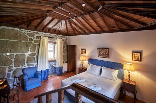 a bedroom with a bed and a blue chair at Solar de Vilar Seco in Vilar Seco