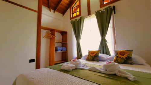 a bedroom with towels on a bed with a window at Arenal Sweet Cabins in Fortuna