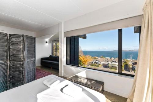 a bedroom with a bed and a large window at Muritai House - Taupo in Taupo