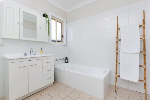 Baño blanco con bañera y lavamanos en Tranquil 2-bedroom retreat en Lake Albert