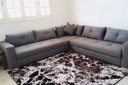a gray couch in a living room with a rug at Villa David front de mer in Bouznika