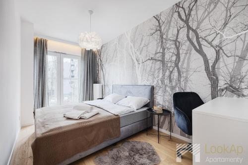a bedroom with a bed and a wall with trees at Diasfera Prestige by LookAp in Łódź