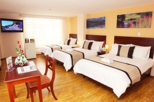 a hotel room with four beds and a table and a desk at Hotel Xilon Pasto in Pasto