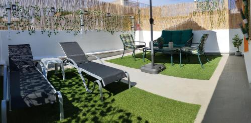 a patio with chairs and a table and grass at Casa Mayago, terraza y solárium in Pego