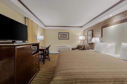 a hotel room with a bed and a flat screen tv at Best Western Premier Denham Inn & Suites in Leduc