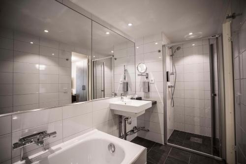 y baño con bañera, lavamanos y ducha. en Scandic Skärholmen, en Estocolmo