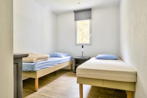 une chambre avec deux lits et une fenêtre dans l'établissement Les Maisons du Domaine du Golf de Pinsolle - maeva Home - Maison 3 pièces 4 personnes - Exclusive - Super Home MAE-5961, à Soustons