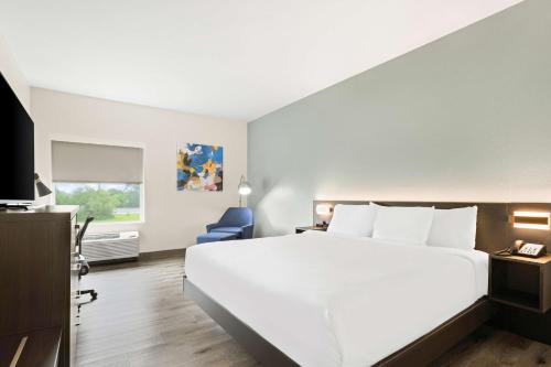 a bedroom with a large white bed and a blue chair at Best Western Iowa - Lake Charles East in Iowa