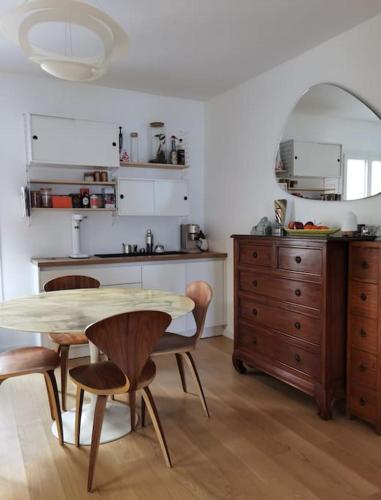 une cuisine avec une table et des chaises en bois, une table et un comptoir dans l'établissement Family duplex apartment Montparnasse St Germain, à Paris