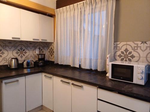 eine Küche mit weißen Schränken und einer Mikrowelle auf der Theke in der Unterkunft Anchorena 1117 Hotel Suite And Hostel in Buenos Aires