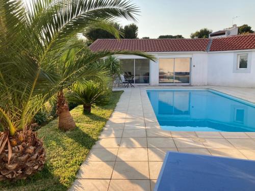 - une piscine à côté d'une maison avec un palmier dans l'établissement Location vacances T1 indépendant avec piscine privée, à Saint-Mitre-les-Remparts