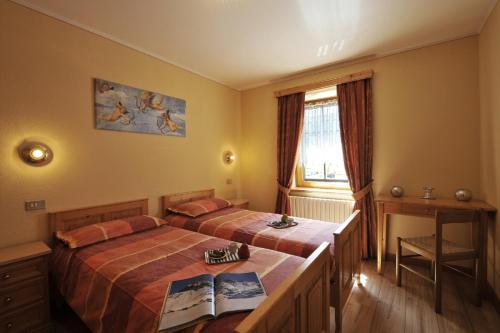 - une chambre avec 2 lits, un bureau et une fenêtre dans l'établissement Genziana - Happy Rentals, à Livigno