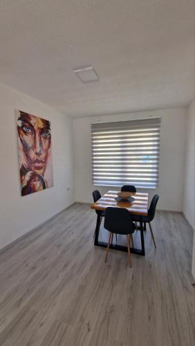 a room with a table and chairs and a painting at East Gate Apartments in Kriva Palanka