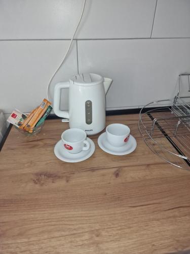 a coffee maker and two cups on a wooden floor at East Gate Apartments in Kriva Palanka