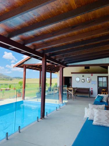 an outdoor patio with a pool and wooden ceiling at Blue Fattoria Luxury Farm Accomodation in Fernside