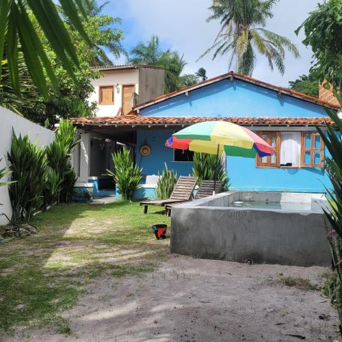 a blue house with a pool and an umbrella at Casa Beija-flor Pousada in Ilha de Boipeba
