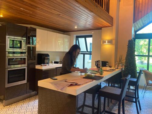 a woman sitting at a kitchen island in a kitchen at Grove House Country Rooms in Shanballymore