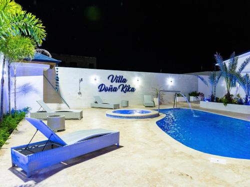 a swimming pool with a blue chair next to a building at Villa doña kika in San Felipe de Puerto Plata