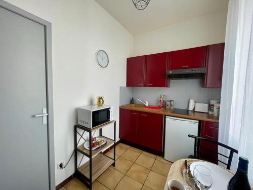 une petite cuisine avec des placards rouges et un four micro-ondes dans l'établissement Cosy au Cœur de Dijon, à Dijon
