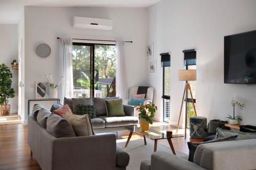 a living room with couches and a flat screen tv at Away - 4 bedroom 2 bathroom family home in Daylesford
