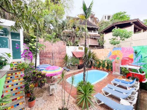 ITH Amazing Hostel Sayulita في سايوليتا: حديقة خلفية بها مسبح وكراسي ومظلة