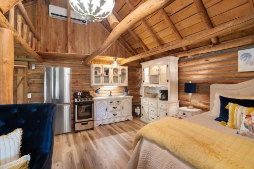 a log cabin bedroom with a bed and a kitchen at Spring Hill Farm - The Velvet Rooster in Alma