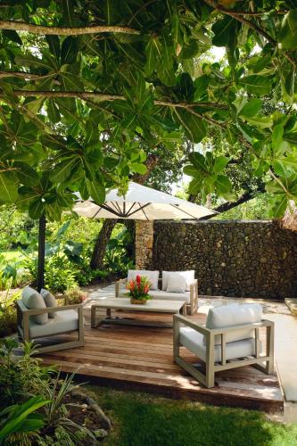 a patio with couches and tables under a tree at Le Taha'a by Pearl Resorts in Motu Tautau