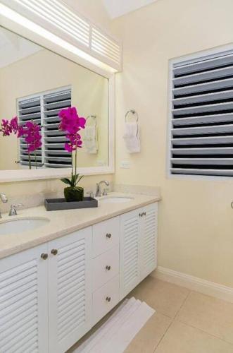 a bathroom with a sink and a mirror and pink flowers at Avant Dream Escape in Richmond