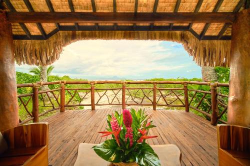 a wooden deck with a table and a vase of flowers at Le Taha'a by Pearl Resorts in Motu Tautau
