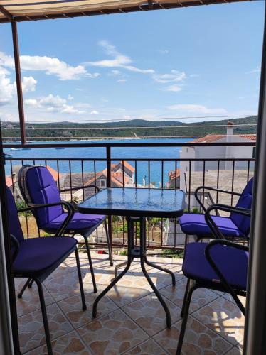 a table and chairs on a balcony with a view of the water at Apartments Vladimir in Primošten