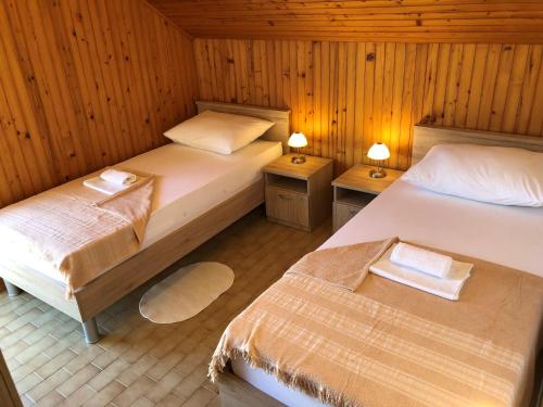 two beds in a room with wooden walls at Apartments Ruza in Ražanj