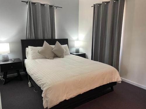 a bedroom with a bed with white sheets and pillows at Alpine Village Jindabyne in Jindabyne