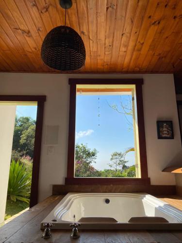 a large bath tub in a room with a window at Chalés Lavras de Minas - Amar in Lavras Novas