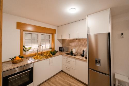 a kitchen with white cabinets and a stainless steel refrigerator at Houses São Pedro in São João da Pesqueira