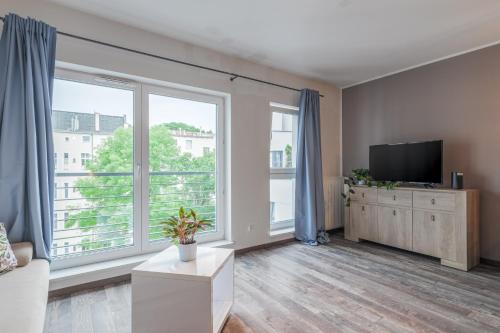 a living room with a tv and a large window at Swarożyca IV - Grysko Apartament's in Szczecin