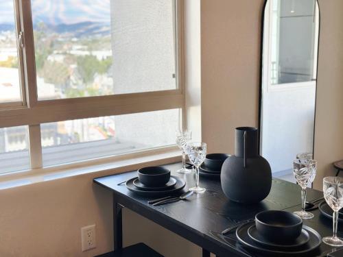 a table with plates and wine glasses and a window at Stylish 1 Bedroom Apartment in LA with Free Parking - 10 Minutes away from Ceders Sinai in Los Angeles