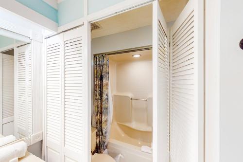 Un baño con paredes blancas y contraventanas y un inodoro. en The Inn at St. Thomas Square #1202c, en Panama City Beach