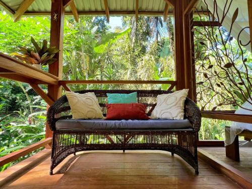 a wicker bench with pillows on a porch at Geckoes Lodge in Cocles