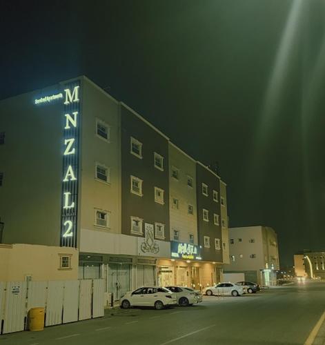 two cars parked in a parking lot in front of a building at منزال الحزم للشقق المخدومة in Ar Rass