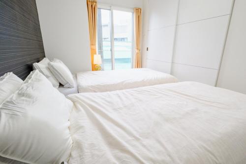 two white beds in a room with a window at AMs海峯楼307 in Otaru