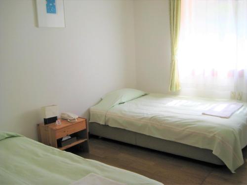 two beds in a small room with a window at Ernest House in Shimoda
