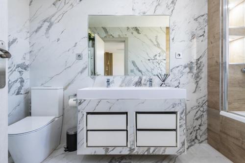 ein weißes Badezimmer mit Waschbecken und Spiegel in der Unterkunft Las Gemas - Chalet adosado en urbanización cerrada in Peñíscola