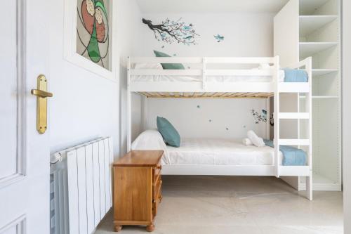 ein Kinderzimmer mit weißen Etagenbetten und einem Schreibtisch in der Unterkunft Las Gemas - Chalet adosado en urbanización cerrada in Peñíscola