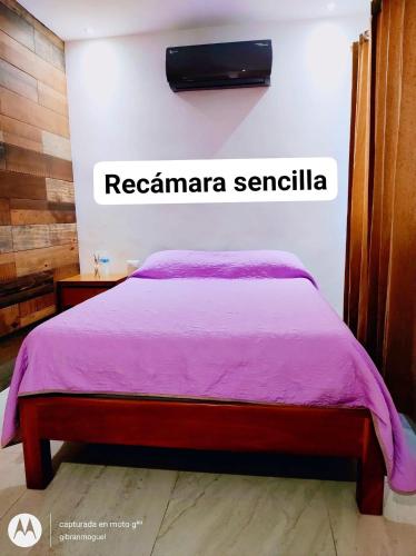 a bedroom with a bed with a pink blanket at Departamentos Túumben Ché in Valladolid
